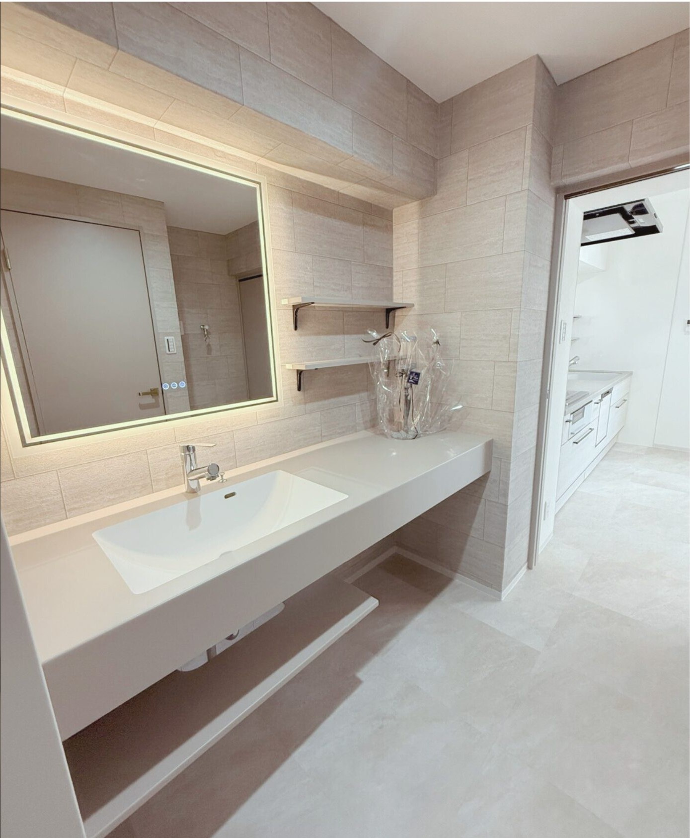 大きな照明付き鏡と造作カウンターがある施工後の洗面室