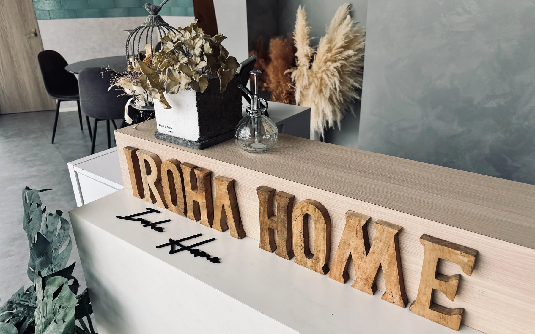 受付カウンターに置かれたIROHA HOMEの木製サインとドライフラワー